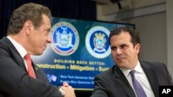 Gov. Andrew Cuomo, left, and Puerto Rico Gov. Ricardo Rossello shake hands at a news conference, Nov. 2, 2017, in New York. Cuomo announced that the state would be sending personnel and trucks to aid in the reconstruction of Puerto Rico's electrical grid.