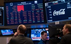 Stocks reflect declines on monitors as people work on the floor of the New York Stock Exchange, Feb. 27, 2020.