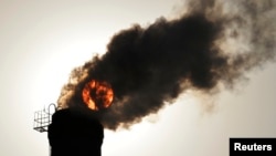 The sun is seen behind smoke from a heating plant.