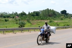 A man ferries a sack of charcoal along a road in Gulu, Uganda on May 28, 2023. Uganda's population explosion has heightened the need for cheap plant-based energy sources, especially charcoal. (AP Photo/Hajarah Nalwadda)