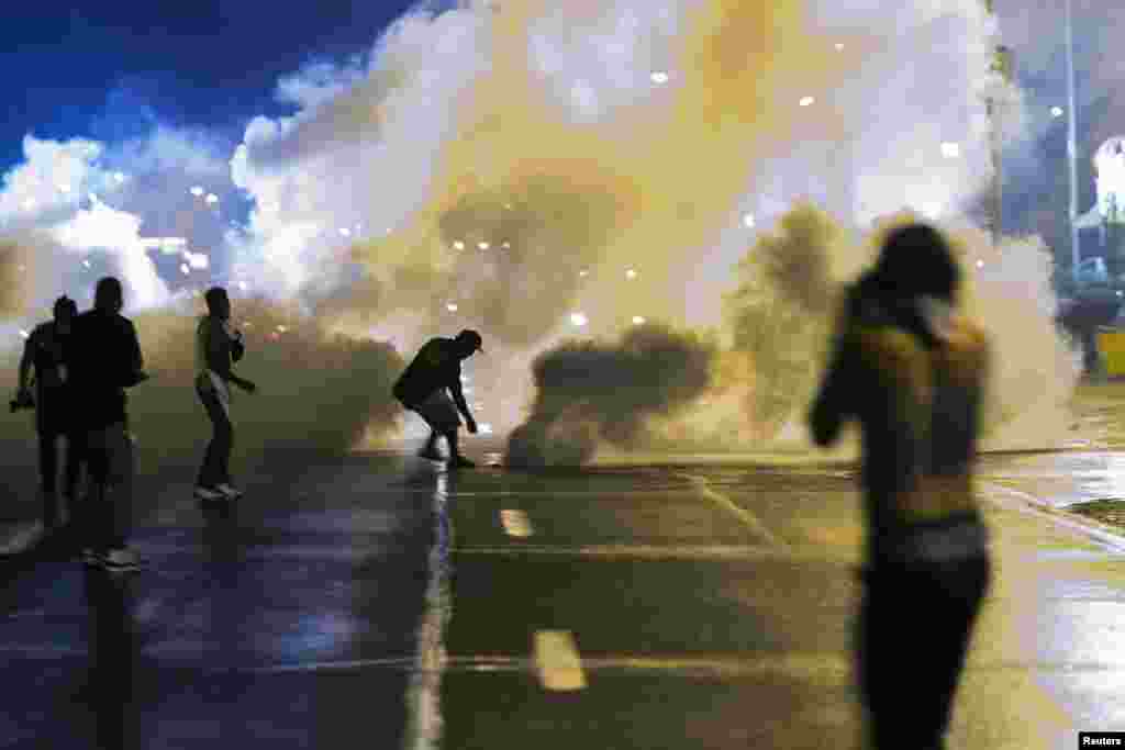 A protester reaches down for a smoke canister from the police during a protest in reaction to the shooting of Michael Brown in Ferguson, Missouri.