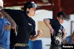 FILE - Damien Chee (L) and Skylar Simon practice drawing their weapon during a firearms training class attended by members of the Pink Pistols, a national pro-gun LGBT organization, at the PMAA Gun Range in Salt Lake City, Utah, July 1, 2016.