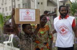 FILE - A child and mother from Makoko slum carry their food parcel distributed by the Nigerian Red Cross, provided for those under coronavirus related movement restrictions, in Lagos, Nigeria, April 25, 2020.