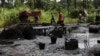 FILE- Men walk past an abandoned illegal refinery in Bayelsa, Nigeria, May 18, 2013. Nigerian authorities in Rivers State unveiled on Friday six military-grade gunboats to help security battle the piracy and oil theft that have plagued the Niger Delta region for decades.