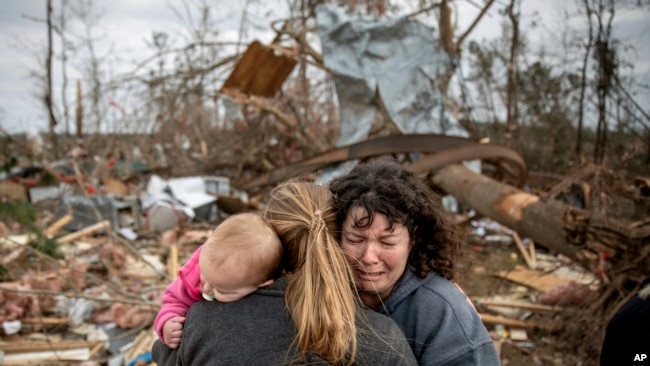 Carol Dean, (derecha) llora mientras es abrazada por Megan Anderson y su hija de 18 meses, Madilyn, mientras Dean busca entre los escombros de la casa que compartía su esposo, David Wayne Dean, quien murió cuando un tornado azotó Beauregard, Alabama, el 3 de marzo de 2019.