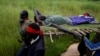 FILE - SPLA-IO (SPLA-In Opposition) rebels carry an injured rebel after an assault on government SPLA (Sudan People's Liberation Army) soldiers, on the road between Kaya and Yondu, South Sudan, August 26, 2017.