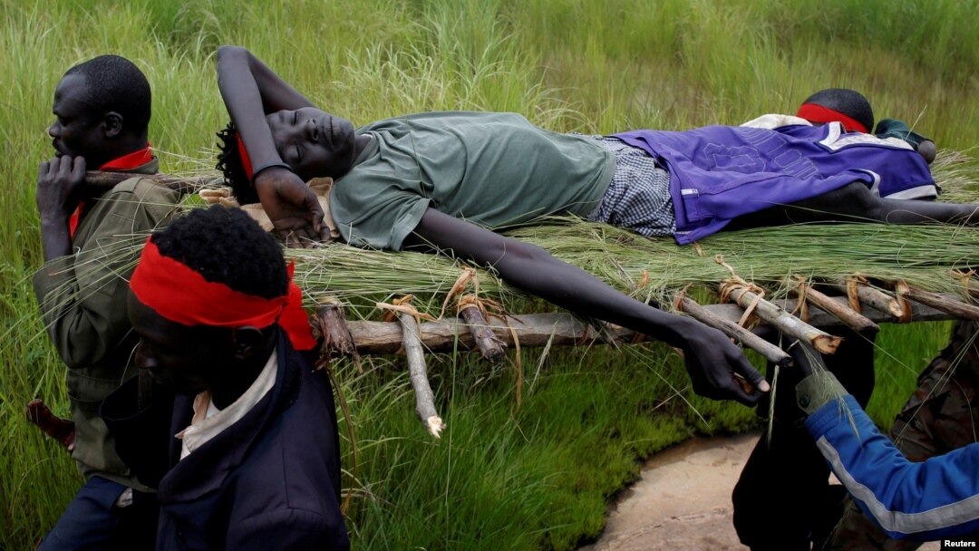 FILE - SPLA-IO (SPLA-In Opposition) rebels carry an injured rebel after an assault on government SPLA (Sudan People's Liberation Army) soldiers, on the road between Kaya and Yondu, South Sudan, Aug. 26, 2017.