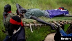 FILE - SPLA-IO (SPLA-In Opposition) rebels carry an injured rebel after an assault on government SPLA (Sudan People's Liberation Army) soldiers, on the road between Kaya and Yondu, South Sudan, Aug. 26, 2017.