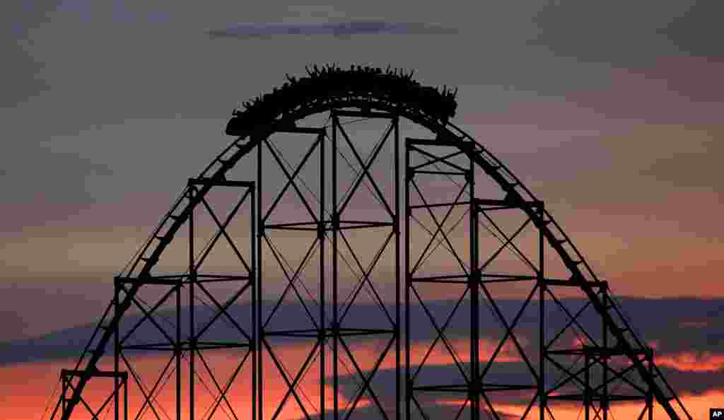 People ride a roller coaster at dusk at the Worlds of Fun amusement park in Kansas City, Missouri, July 3, 2017.