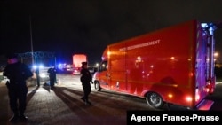Police officers stand next to a fire command centre arriving at Calais harbor after 27 migrants died in the sinking of their boat off the coast of Calais, Nov. 24, 2021. 