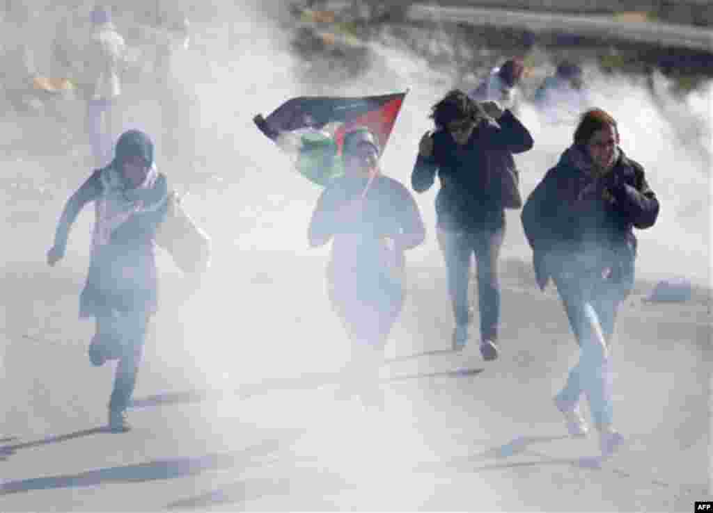 Activists run away from tear gas during a protest against the expansion of the nearby Jewish settlement of Halamish in the West Bank village of Nabi Saleh, near Ramallah, Friday, Jan. 6, 2012. (AP Photo/Majdi Mohammed)