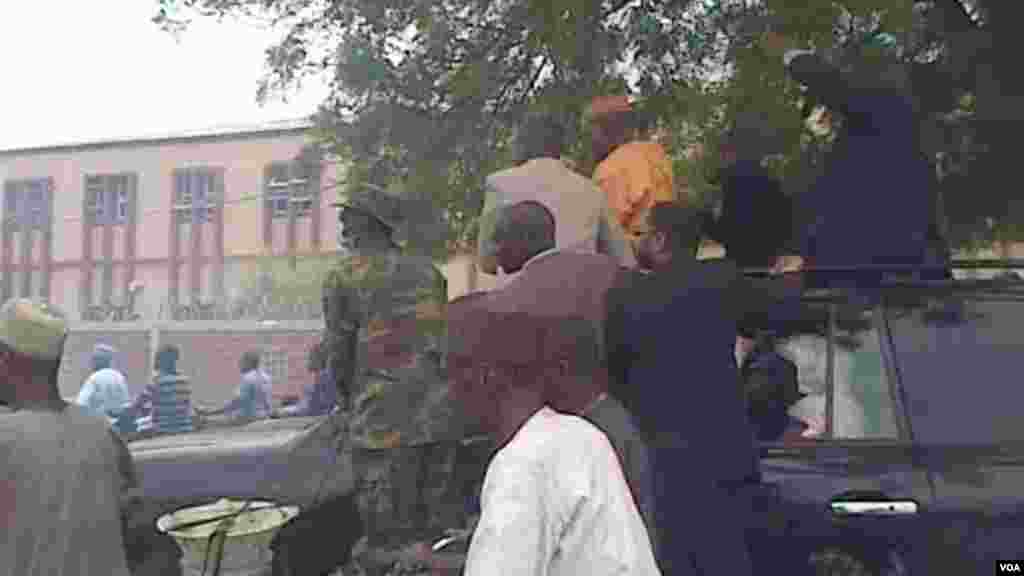 Manjo Hamza Al-Mustapha waves to people escorting him as he arrives in Kano.