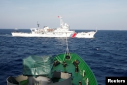 FILE - A ship (top) of the Chinese Coast Guard is seen near a ship of the Vietnam Marine Guard in the South China Sea, about 210 km (130 miles) off shore of Vietnam, May 14, 2014