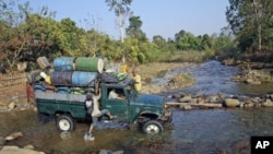 A man leaps onto a truck as it forges a creek in a rural part of Burma's Kachin state, February 26, 2012.