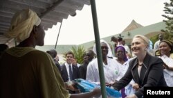 U.S. Secretary of State Hillary Clinton (R) gives a mosquito net for malaria prevention to a local woman during a tour of the Philippe Senghor Health Center in Dakar, Senegal, August 1, 2012.