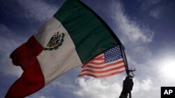 Un migrante ondea las banderas de México y Estados Unidos a su paso por el paso fronterizo del Chaparral, en Tijuana, México, el 22 de noviembre de 2018.