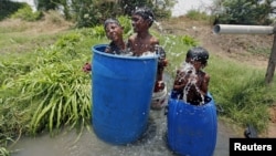 Children sit in plastic containers filled with water as they cool themselves next to a borewell at a farm on a hot summer day on the outskirts of Ahmedabad, India, May 28, 2015.