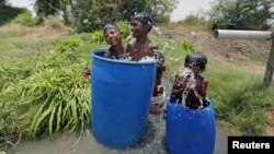 Anak-anak di Ahmedabad, India mendinginkan diri di dalam bak plastik (28/5). Jumlah korban tewas akibat gelombang panas di India telah bertambah menjadi lebih dari 1.800 orang, kata para pejabat hari Jumat (29/5). (Foto: REUTERS/Amit Dave).