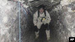 A San Diego Tunnel Task Force agent crouches inside a cross-border tunnel that authorities say was used as an underground drug passage, in San Diego, California, 26 Nov 2010