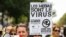 A woman wearing a yellow vest and speaking in a loud hailer, holds a placard reading "Media are the virus ..." during a demonstration against the mandatory COVID-19 health pass in Paris on Sept. 4, 2021