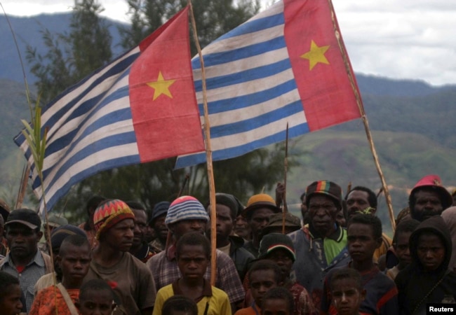 Pendukung Gerakan Papua Merdeka mengibarkan bendera Bintang Kejora saat upacara pengibaran bendera di Kabupaten Paniai Timur, Papua, 17 Oktober 2008. (Foto: REUTERS/Muhammad Yamin)