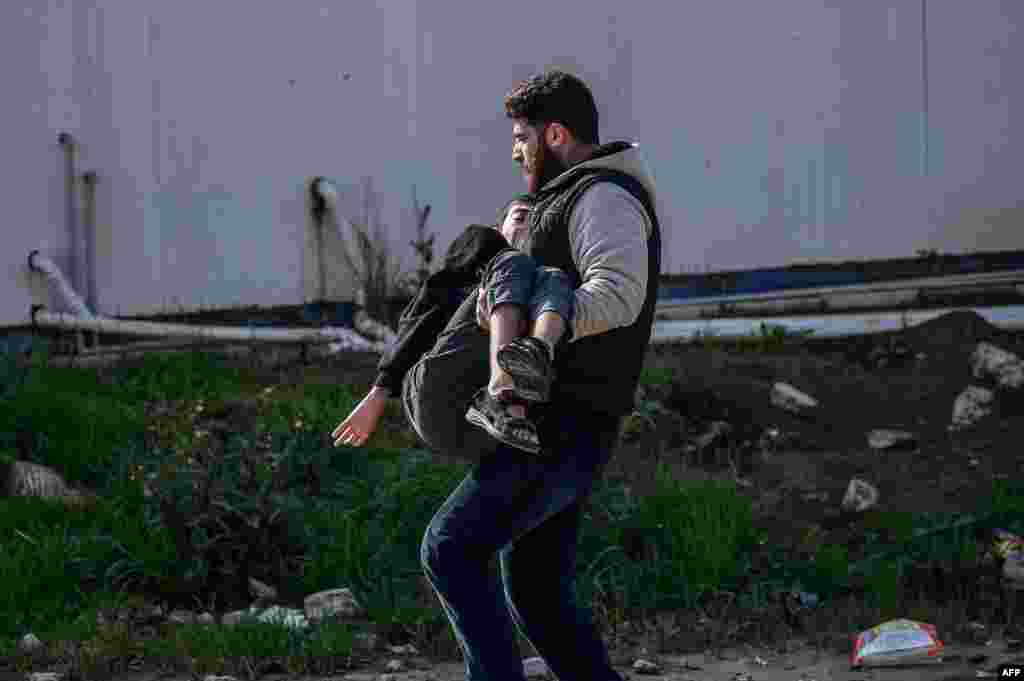 A man carries an injured man after a rocket hit a road in the Reyhanli district in Hatay province, near the Turkey-Syria border.