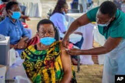 FILE - A woman receives a coronavirus vaccination at the Kololo airstrip in Kampala, Uganda, May 31, 2021.