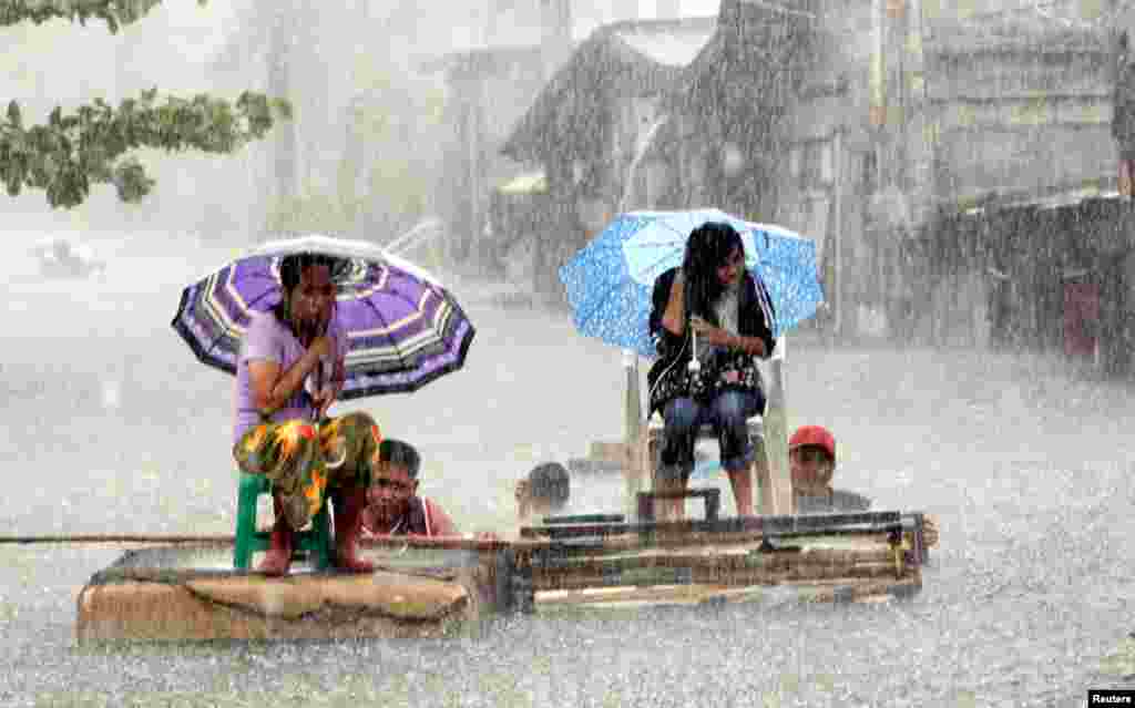 Warga mengendarai rakit di jalanan yang terendam banjir di Malabon, Manila (2/8).