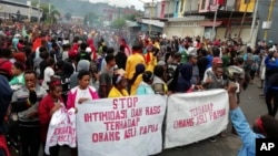 Orang-orang memasang spanduk bertuliskan "Hentikan intimidasi dan rasisme terhadap orang asli Papua" selama protes di Manokwari, Papua, Senin, 19 Agustus 2019. (Foto: AP)