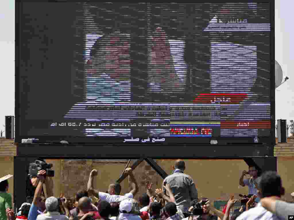 Ousted President Hosni Mubarak  is seen on TV screen as he enters the courtroom on a hospital bed, outside the  Police Military Academy complex in Cairo. (AP Image)