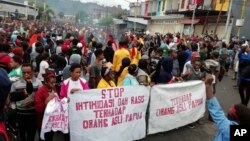 Orang-orang memasang spanduk bertuliskan "Hentikan intimidasi dan rasisme terhadap orang asli Papua" selama protes di Manokwari, Papua, Senin, 19 Agustus 2019. (Foto: AP)