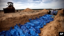 FILE - Palestinians pray over bodies of people killed in the Israeli bombardment who were brought from the Shifa hospital before burying them in a mass grave in the town of Khan Younis, southern Gaza Strip, November 22, 2023.