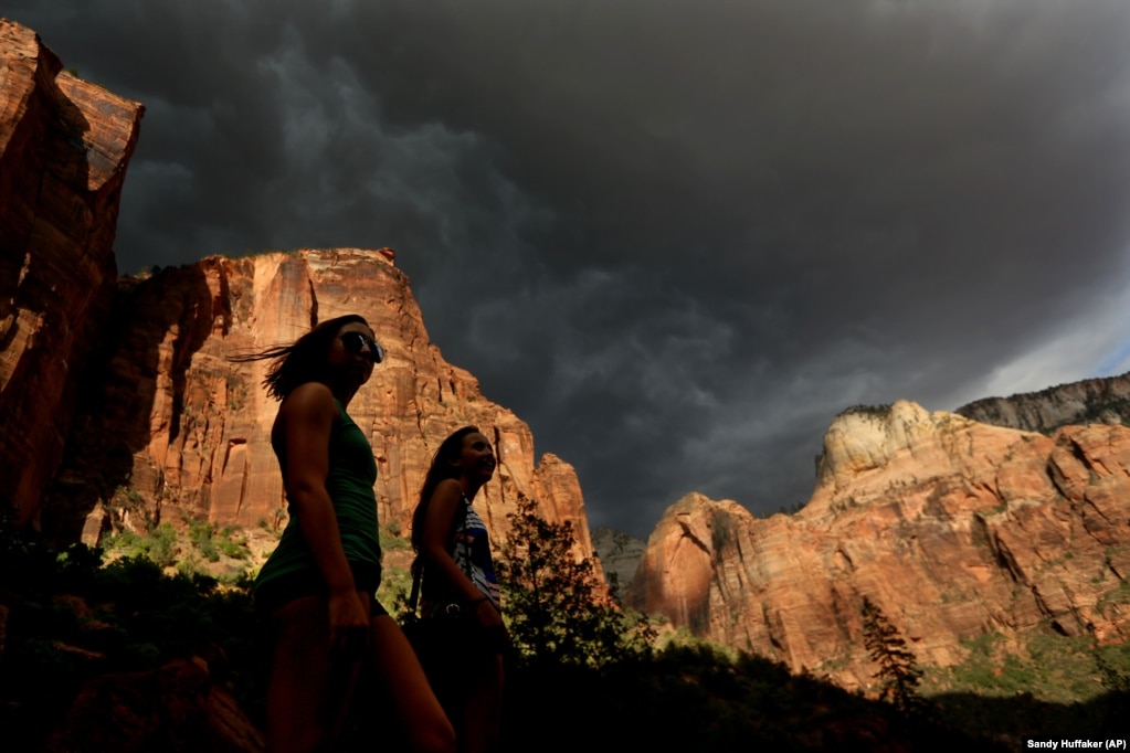 Hikers look up at a fast moving storm as it makes its way through Zion National Park outside of Springdale, Utah. Many of the country's most prominent national parks, including Grand Canyon, Yellowstone and Zion, set new visitation records in 2015. 