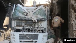 FILE - A civil defense member inspects the damage after the agency's center was hit by an airstrike in a rebel-held area of Aleppo, Syria, Aug. 12, 2016.