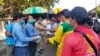 FILE: In this Jan. 27, 2020, photo provided by the Poipet International Checkpoint, government officials distribute face masks to tourists during a launch of a plan to distribute a million masks to travelers arriving at the checkpoint with Thailand as a safety precaution against 