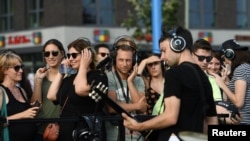 Personas con auriculares escuchan a la banda "von Welt" durante un "Concierto Silente" en la Galería East Side de Berlín, Alemania, el 10 de agosto de 2019.