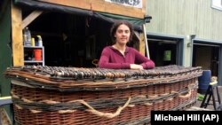 Mary Lauren Fraser stands beside a coffin she hand-wove from willow, in Montague, Mass. Fraser sells biodegradable, hand-woven urns and coffins for use in green burials. 