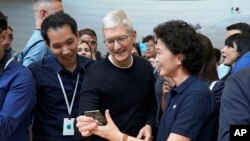 Apple CEO Tim Cook, center, looks at the the new iPhone 11 Pro Max, during an event to announce new products Tuesday, Sept. 10, 2019, in Cupertino, Calif. (AP Photo/Tony Avelar)