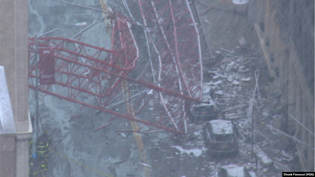 Une grue est tombée du haut d&rsquo;un immeuble et s&rsquo;est écrasée au sol contre des véhicules, causant au moins un mort et trois blessés dans une rue de New York City, 5 février 2016. Chuck Forcucci (VOA New York Bureau)