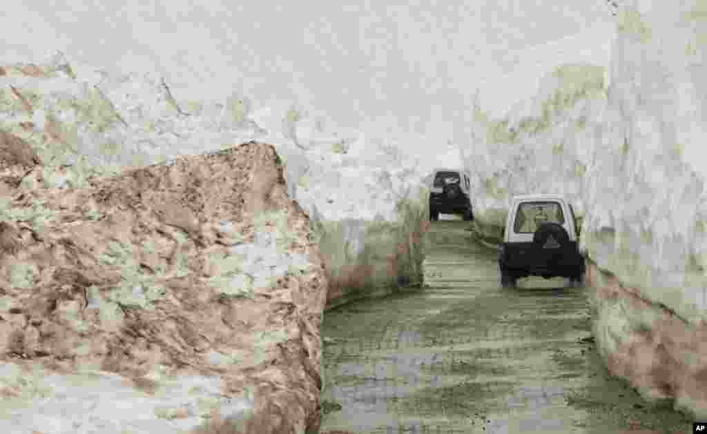 Vehicles drive past walls of snow on the Zojila Pass road, about 110 kilometers north of Srinagar, India.