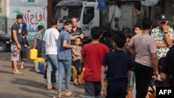 Ljudi u gradi Gazi stoje u redu kako bi sipali svežu vodu (Foto: MOHAMMED ABED / AFP)