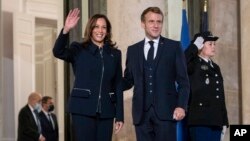 French President Emmanuel Macron stands next to U.S. Vice President Kamala Harris as she waves before a bilateral meeting at Élysée Palace in Paris, France, Nov. 10, 2021. 