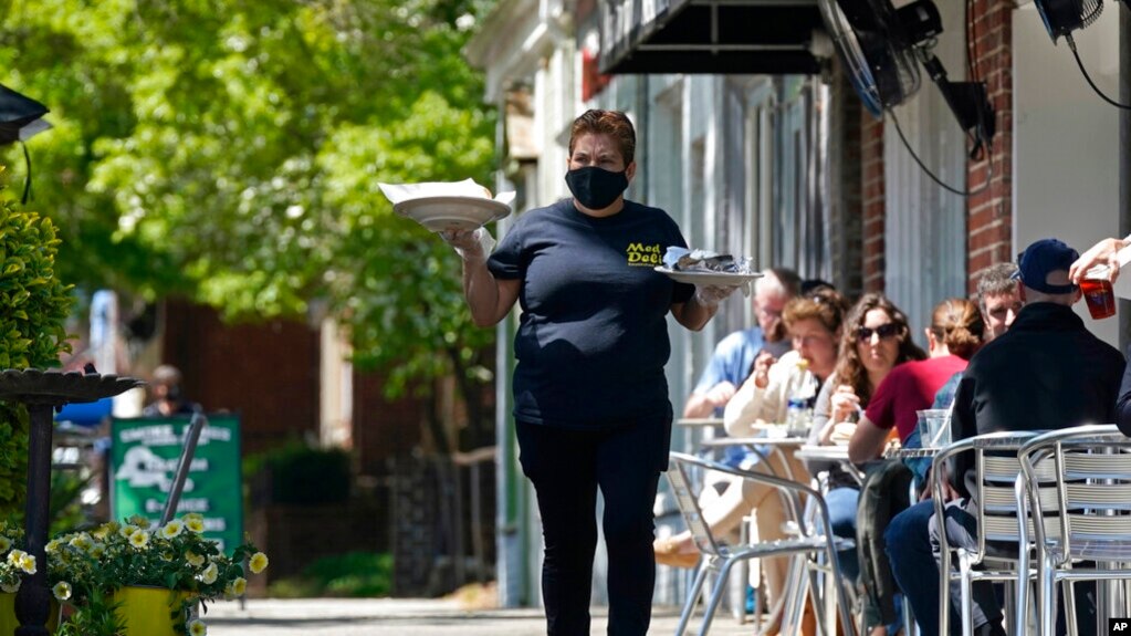 一名餐馆服务员在北卡罗来纳州教堂山的地中海熟食店的人行道上用餐的顾客上菜。上个季度，美国经济以6.4％的年增长率快速增长。(photo:VOA)