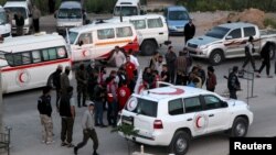 Buses and ambulances evacuating people from four besieged Syrian towns wait at an exchange point supervised by the Syrian Arab Red Crescent, in the town of Qalaat al-Madiq, in Hama province, Syria, April 21, 2016. 