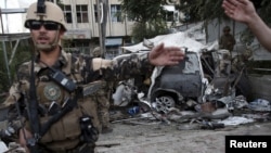阿富汗安全部隊的成員在一輛被炸彈爆炸所損壞的外國車前進行巡查（2015年8月22日）。