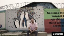 Jorge Santiago Ávila Corrales, 33 años, director de Jóvenes Contra la Violencia (JCV) se sienta frente a graffitis hechos por JCV durante las actividades comunitarias en Choloma, San Pedros Sula, Honduras. [Foto: cortesía de Nicolo Filippo Rosso, ACNUR]