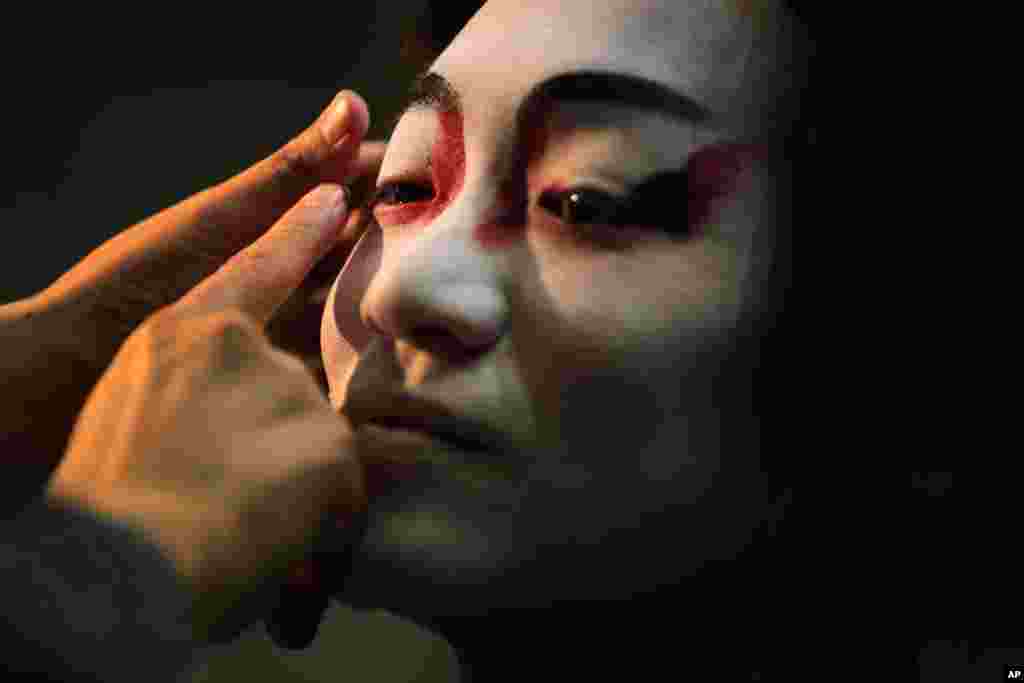 A professional artisan of kabuki makeup paints a man&#39;s face with a pattern of makeup called &quot;Kumadori&quot; at an art event in Tokyo, Japan.