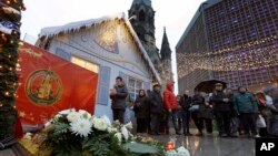 A man takes a picture of candles and flowers after the reopening of the Christmas market at the Kaiser Wilhelm Memorial Church in Berlin, Germany, Dec. 22, 2016, three days after a truck ran into the crowded market and killed several people.