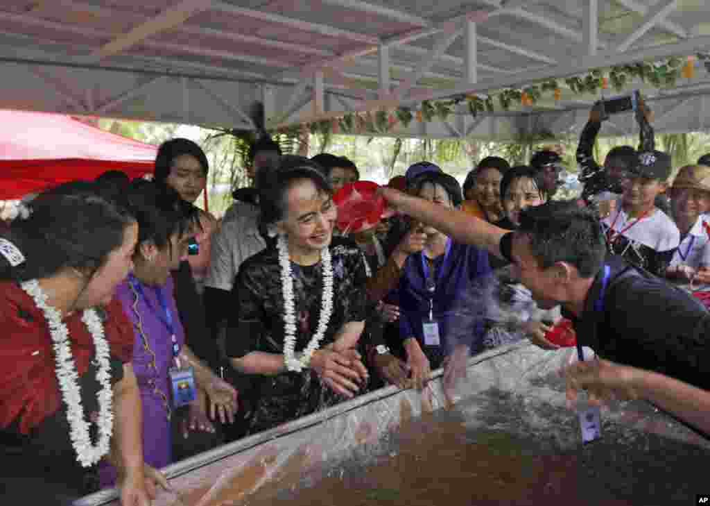 Myanmar&#39;s State Counselor Aung San Suu Kyi, center, is doused with water by a man as she takes part in the last day of the country&#39;s traditional water festival, also known as Myanmar New Year, in Naypyitaw.