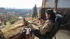 A fighter affiliated with Syria's new administration checks his phone as he sits outside the defunct Mezzeh military prison overlooking the capital, Damascus, Jan. 2, 2025.